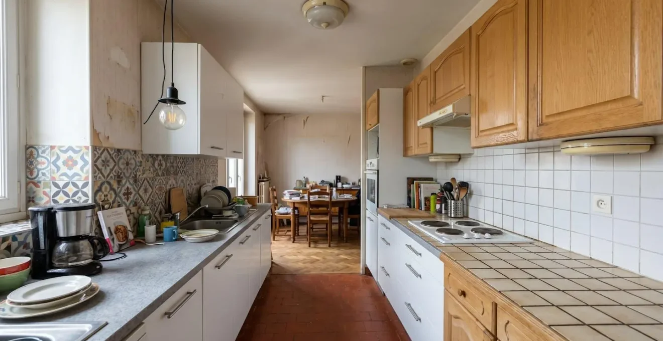 Cuisine présentant un mélange incohérent de styles avec façades modernes, plan de travail inadapté et crédence qui ne s'harmonise pas